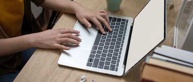 A close-up shot of a student's hands typing on a laptop. The screen displays an AI-powered writing assistant suggesting improvements to a college application essay. The background is blurred, focusing on the screen and the student's attentive expression.