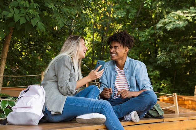 Two college students are sitting on a bench, having a heartfelt conversation. One student is offering a comforting hand on the other's shoulder, showing support and empathy. The setting is a sunny campus quad.