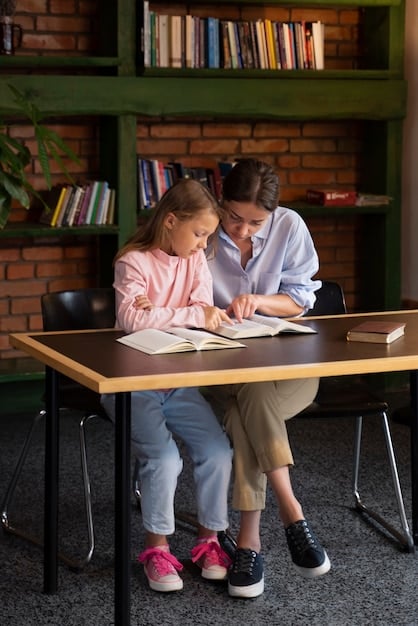 A parent and a teacher are sitting across from each other at a table, reviewing documents. They are both smiling and engaged in a collaborative discussion. A child is sitting beside the parent, looking attentively at the documents. The setting is a quiet and comfortable meeting room in a school.