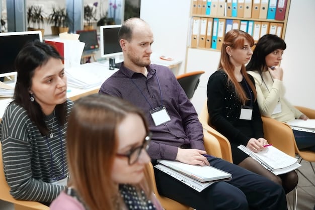 A classroom setting with adults of various ages and backgrounds attentively listening to an instructor. The instructor is pointing to a whiteboard with diagrams and notes related to a specific job skill, such as coding or data analysis.