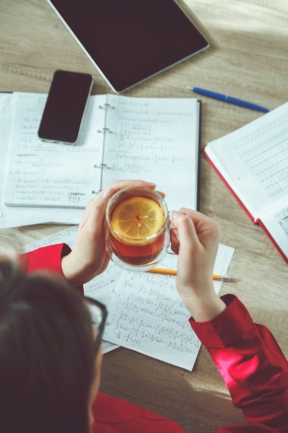 A close-up shot of a student's hands typing a college transfer essay on a laptop, with a cup of coffee and a notebook with handwritten notes nearby.