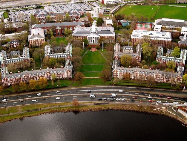 An aerial view of a US university campus showing a mix of modern and historic buildings, surrounded by trees and green spaces, with students walking and biking between classes, capturing the vibrant campus community.