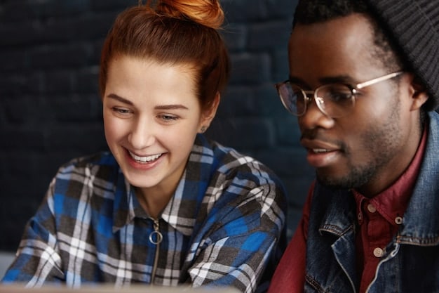 A close-up image of two students, one from the US and one from another country, collaborating on a project. They are both smiling and appear to be deeply engaged in their work.