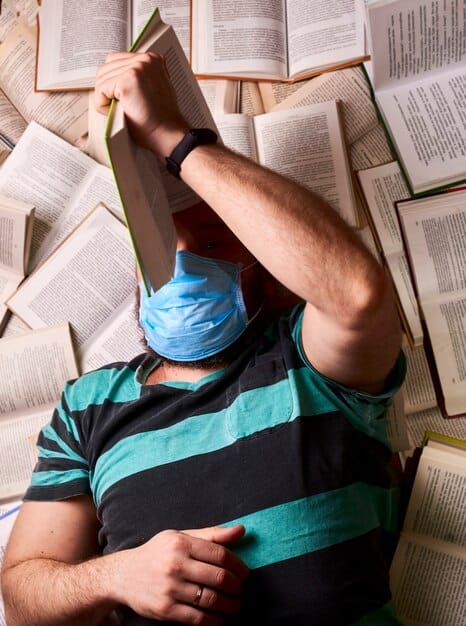 A close-up shot of a student looking overwhelmed while studying in a library, surrounded by books and notes, highlighting the academic stress and pressure.