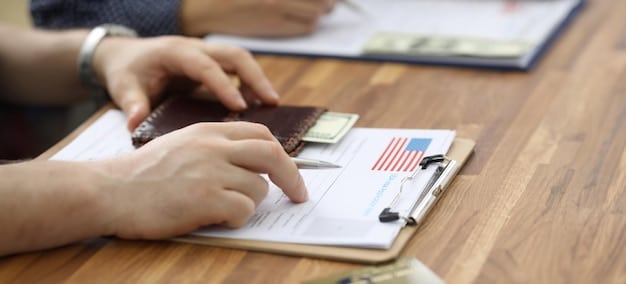 A close-up shot of a government official's hand signing documents related to an unemployment benefits extension program, with the US flag subtly visible in the background.