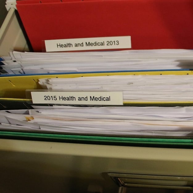 A close-up of various receipts organized in a file folder, categorized by type: medical, charitable, and home expenses. Each receipt is clearly visible, emphasizing the importance of record-keeping for tax deductions.