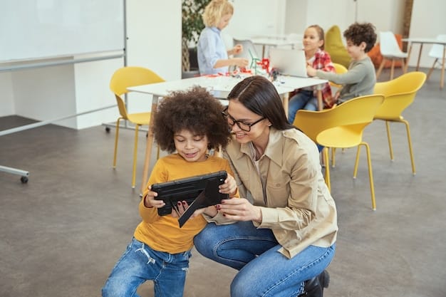 A teacher smiling and interacting with a small group of students around a table, using tablets and educational apps. The classroom is colorful and well-equipped.