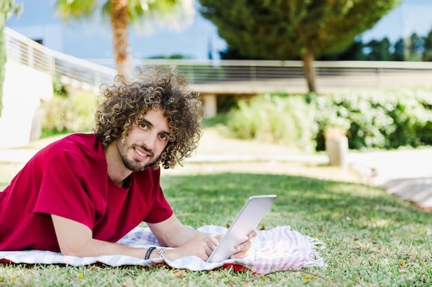 A picture showcasing a college student studying outdoors on a sunny summer day. The scene captures the student with books and a laptop, surrounded by the green lawns and trees of the campus, highlighting the relaxed yet productive atmosphere of summer courses.