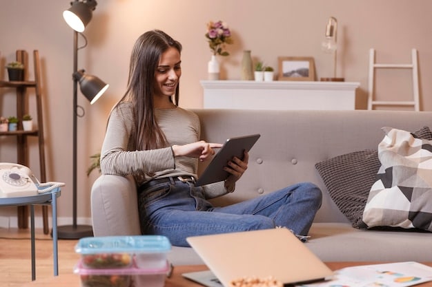 A person using a budgeting app on their smartphone, displaying categorized expenses and savings goals. The background shows a cozy living room with financial self-help books on a shelf.