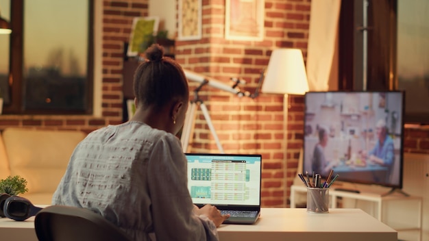 A person sitting at a desk, using a laptop to research credit card interest rates. Multiple browser tabs are open, displaying various finance websites and comparison charts.