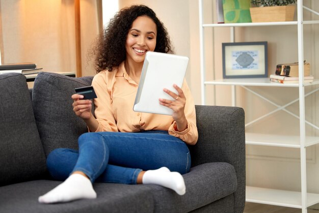 A person using a tablet to compare different credit card offers and balance transfer options. The background shows a comfortable living room setting.